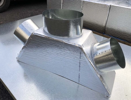 Close-up of a fabricated sheet metal duct junction and pipework