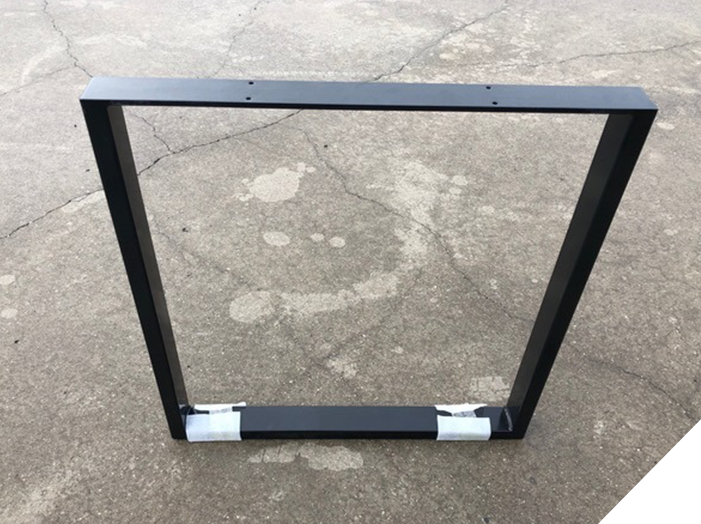 Black metal fabrication frame photographed on a workshop floor